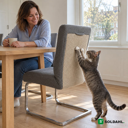 Kvinna vid köksbordet ler åt katten som klöser sisalen på en stol med Klöra