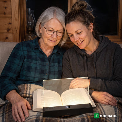 Mor och dotter läser tillsammans med Läsro under en filt på kvällen