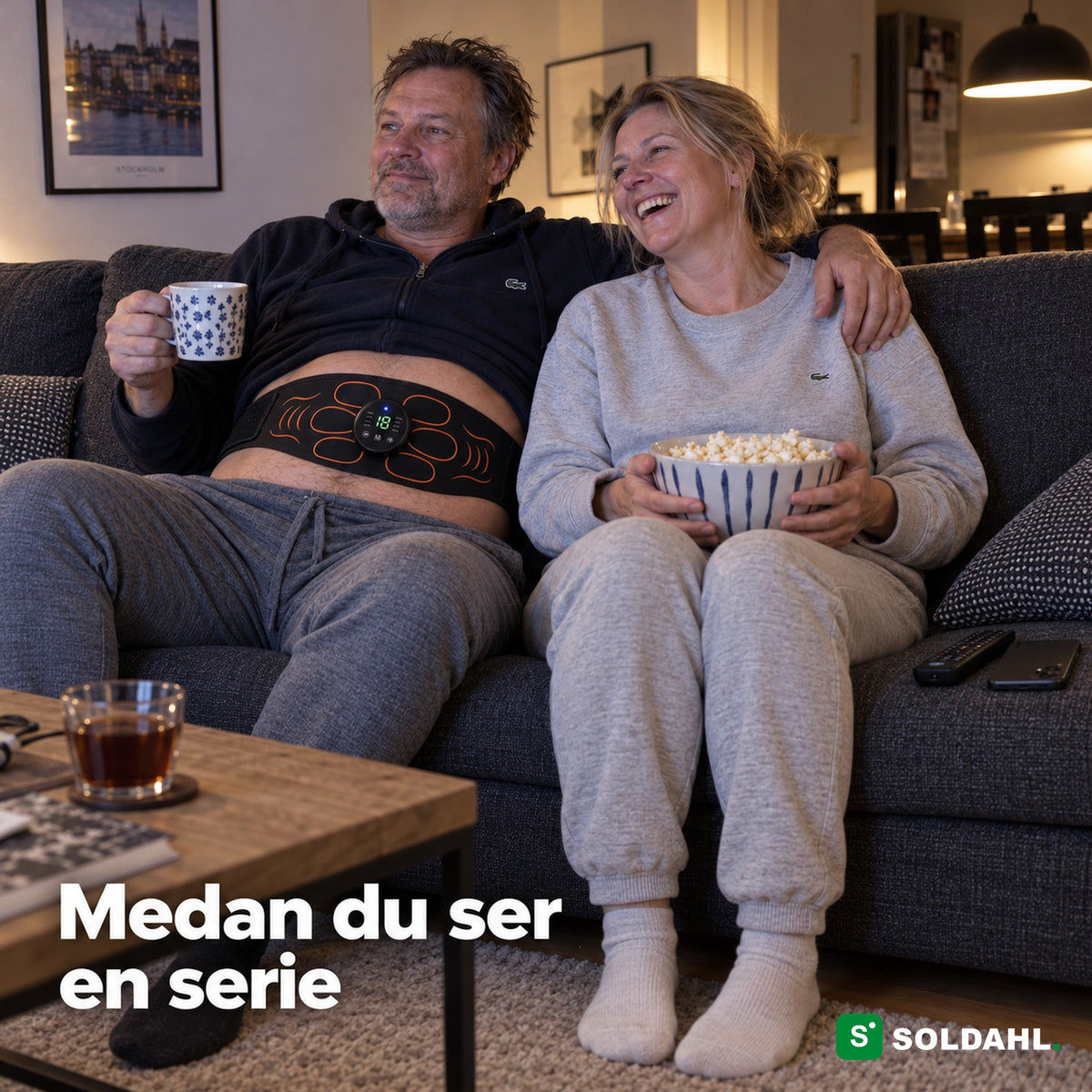 Par i soffan på kvällen, mannen har magbältet på medan de ser en serie