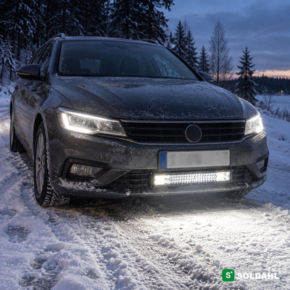 LED-ramp monterad under stötfångaren på en bil på en snöig väg i skymning