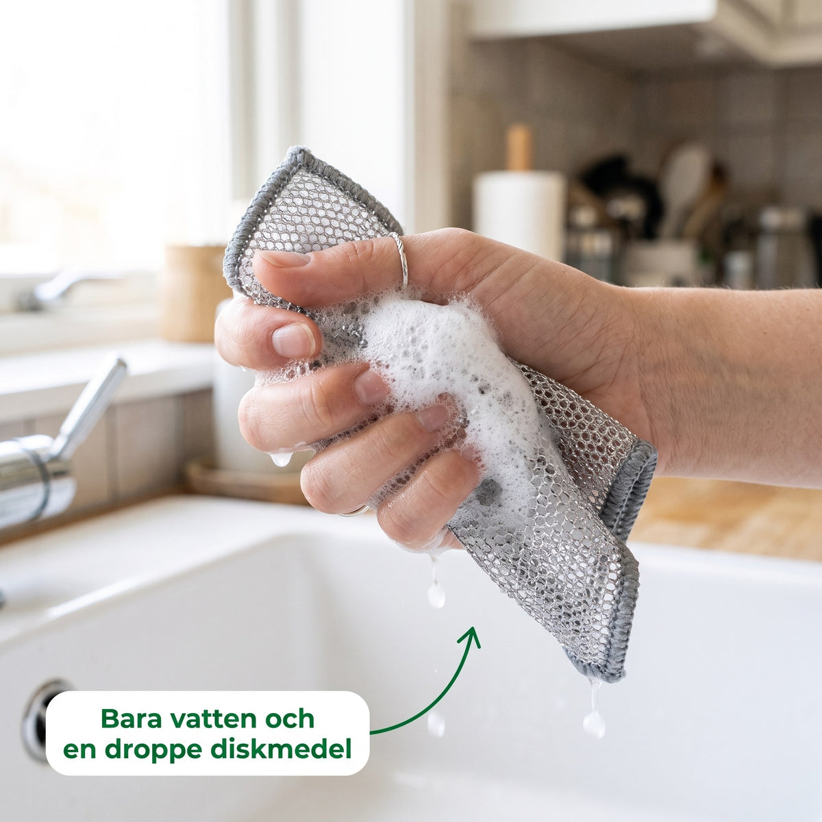 Skurro med vatten och en droppe diskmedel löddrar i handen