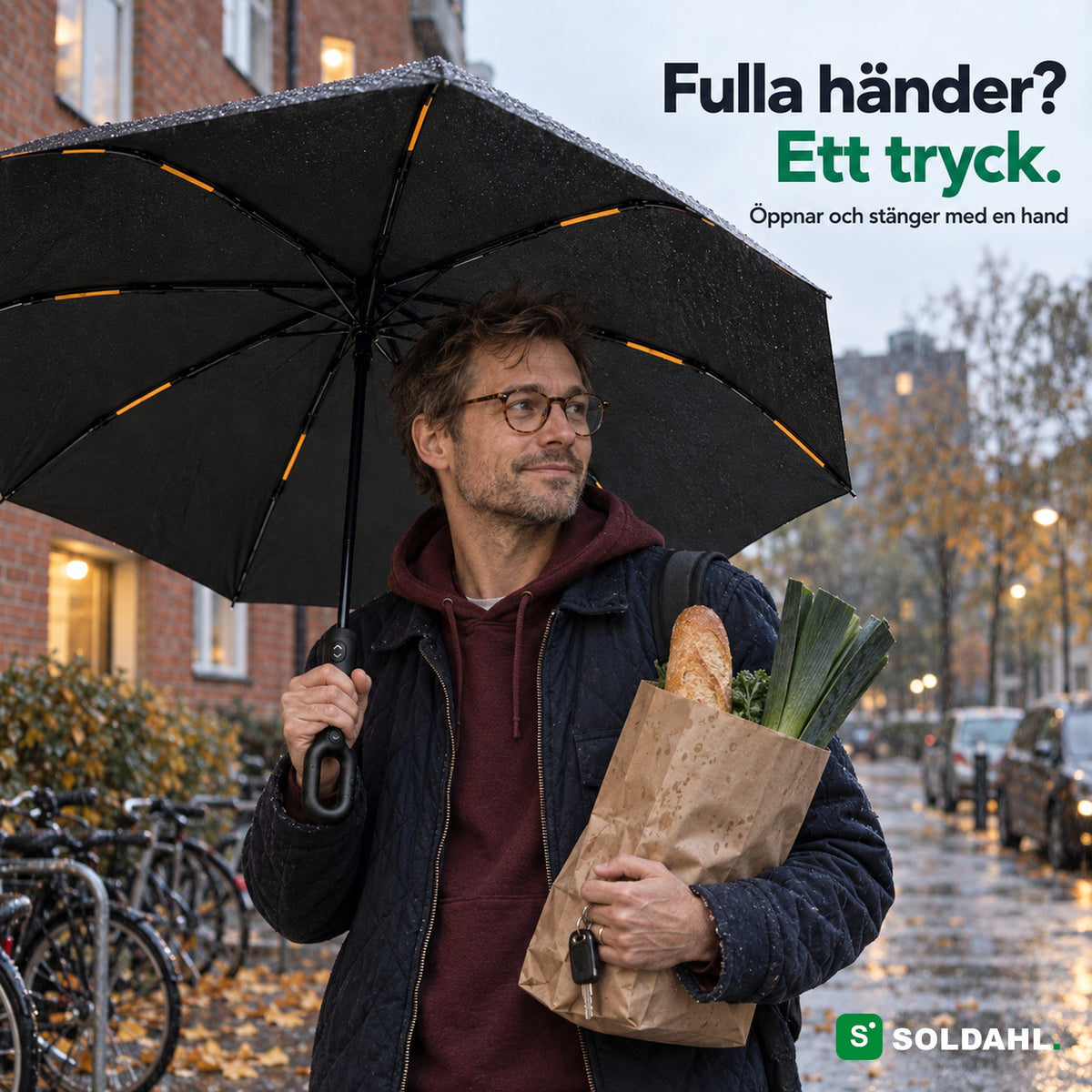 Man med matkasse håller Stormparaplyet i ringhandtaget med en hand i regnet