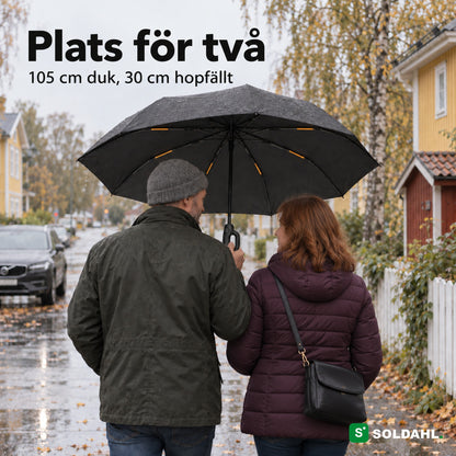 Två vuxna går tillsammans under ett Stormparaply på en regnig villagata