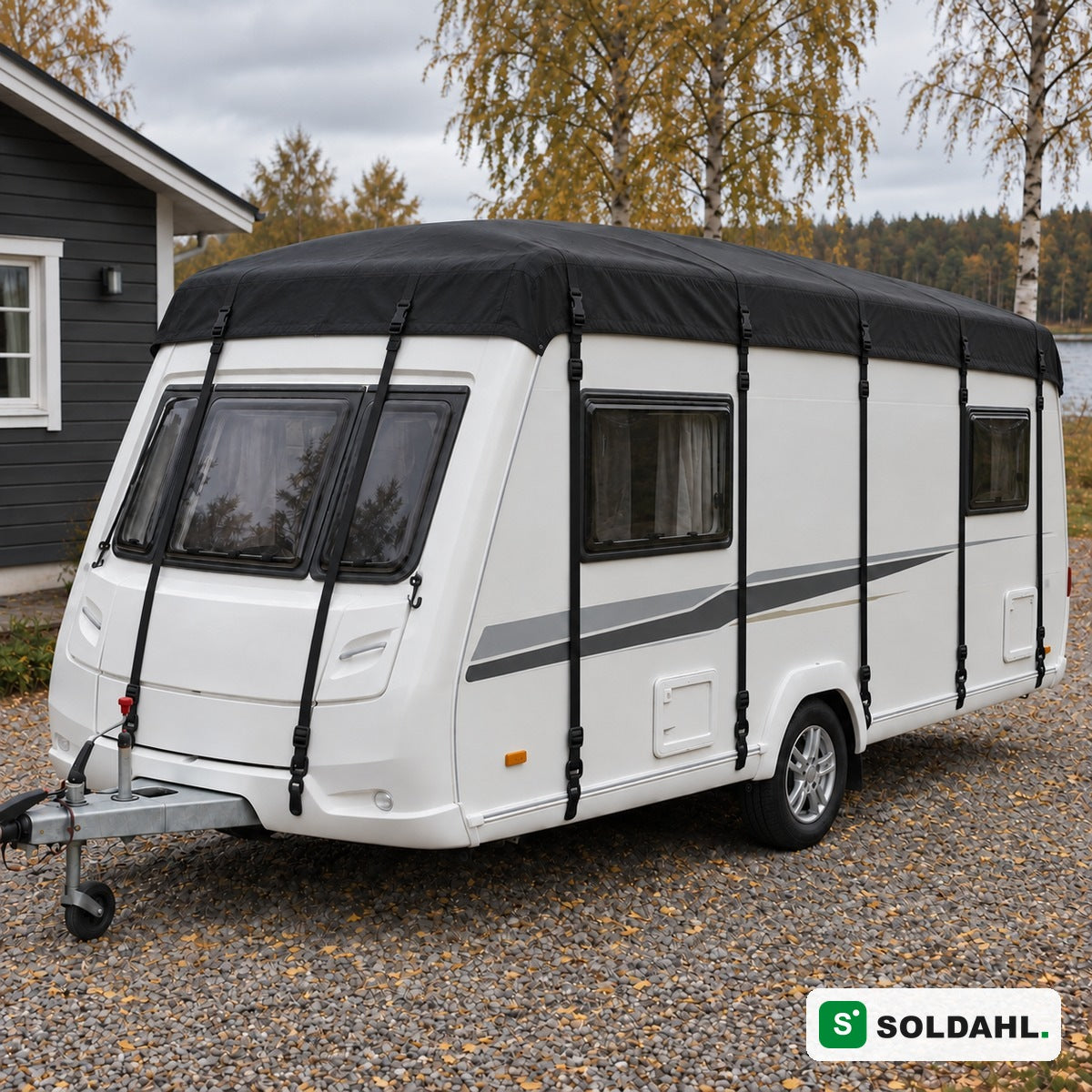 Svart takskydd monterat på vit husvagn på grusuppfart